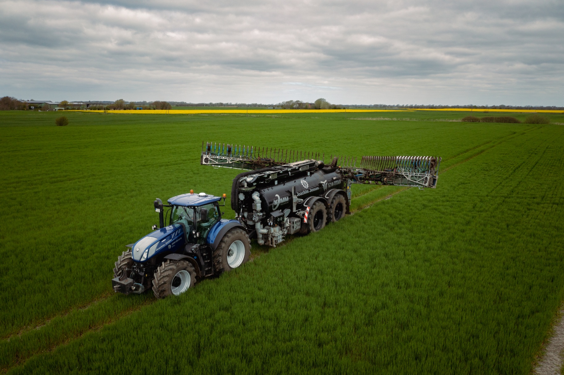 Traktor mit Gülle-Schleppschlauchverteiler im Feld
